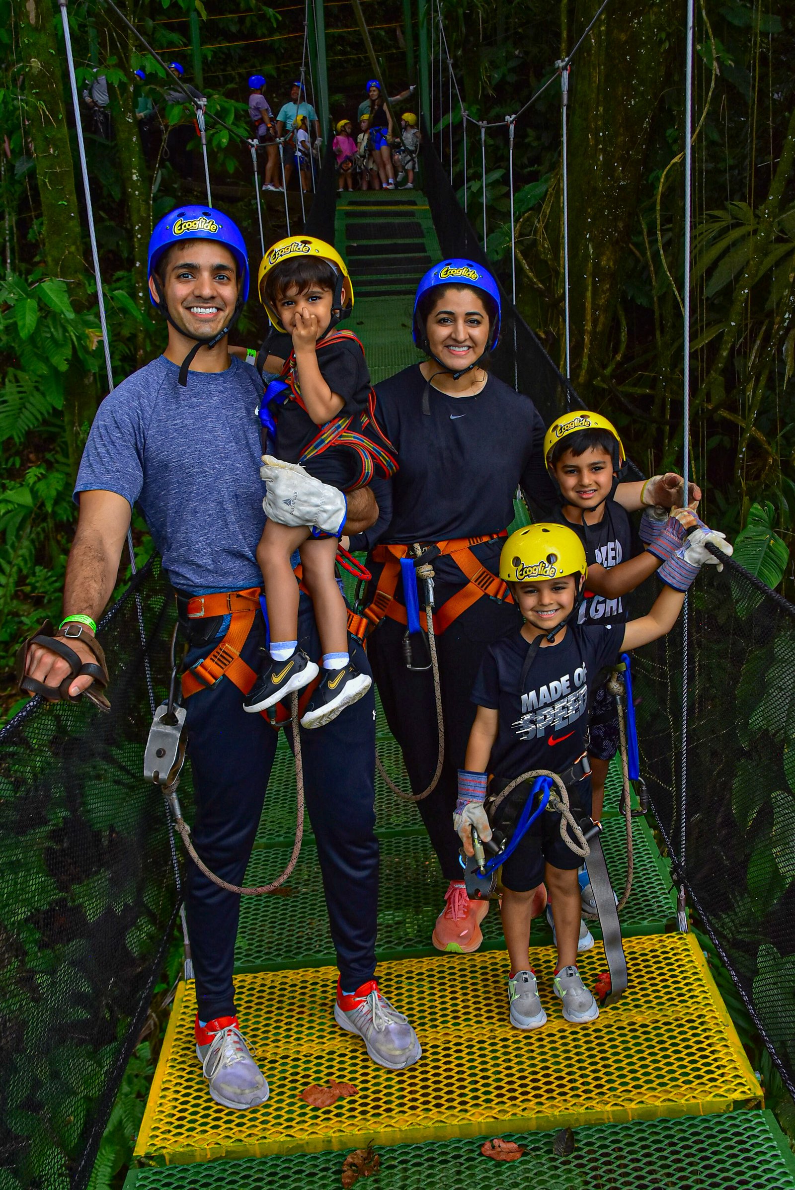 Famille avec casques et harnais sur un pont suspendu dans la forêt de l'Arenal