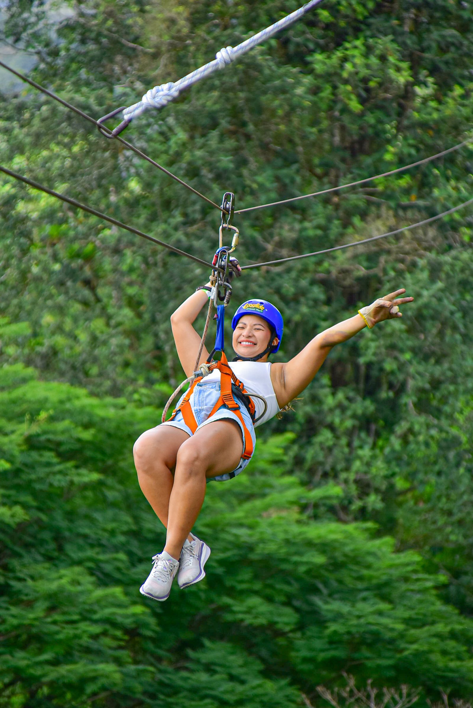 Femme sur une tyrolienne au-dessus de la canopée à l'Ecoglide Arenal Park